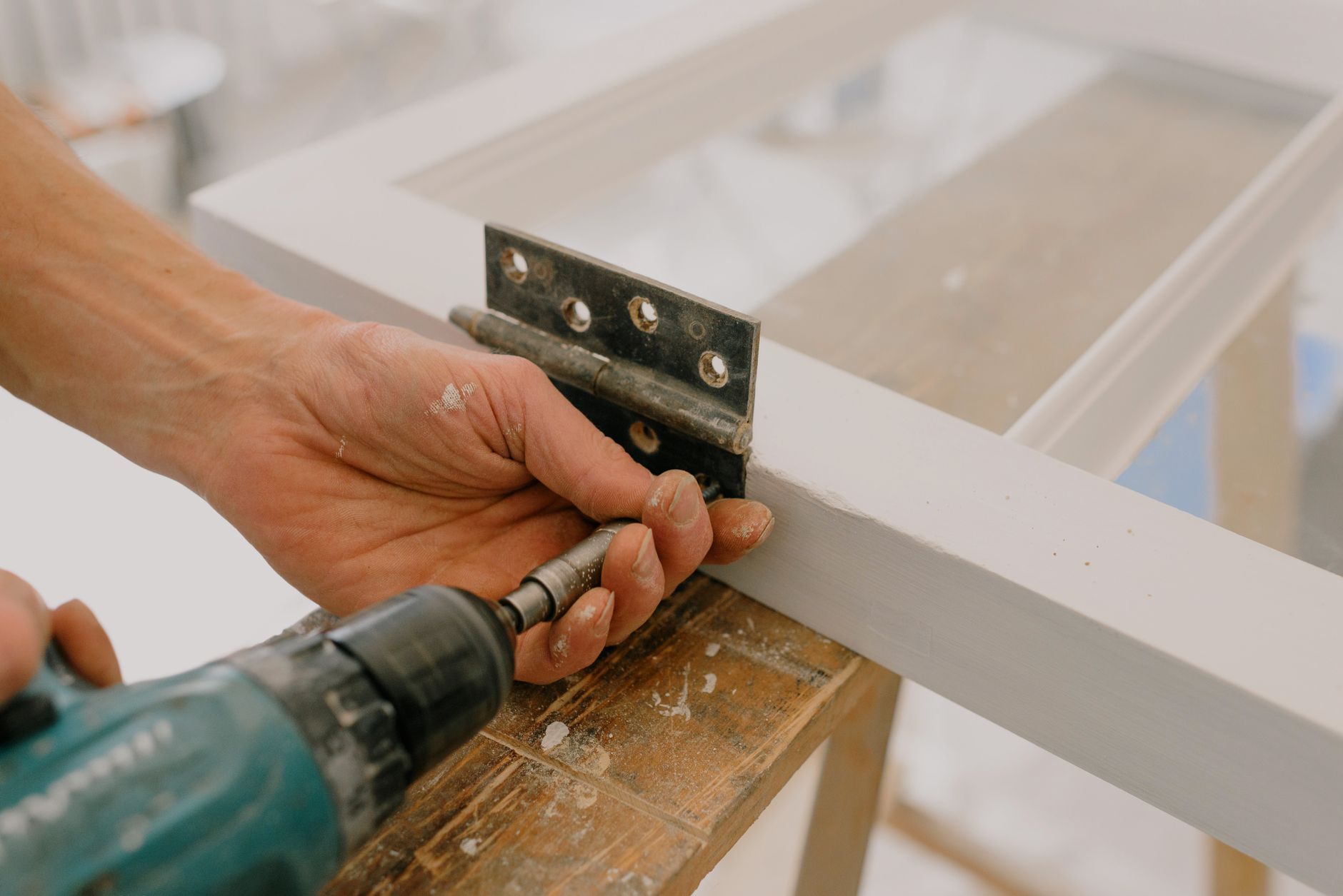Handyman installing a hinge on a door frame